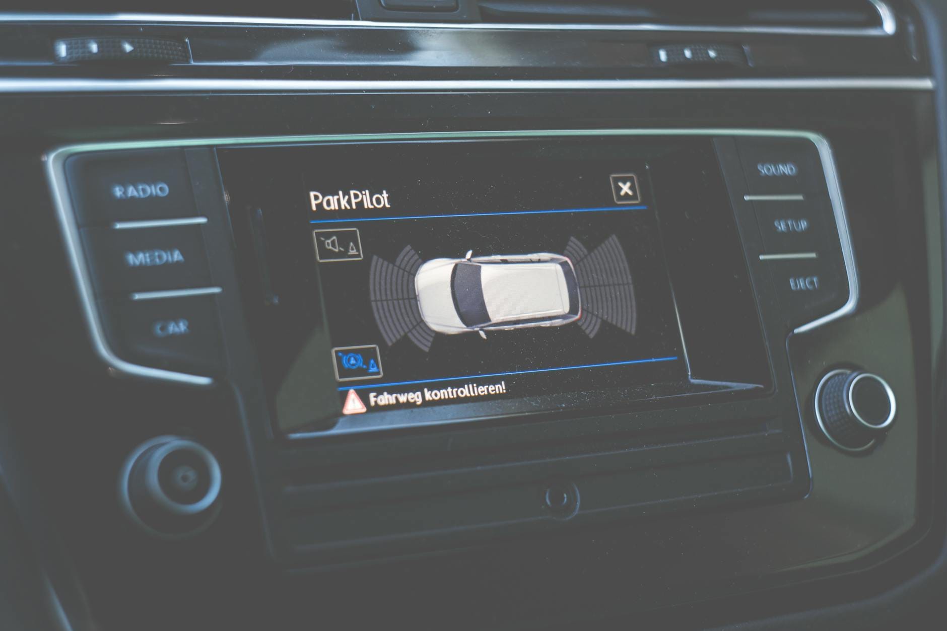 Panel auta z ekranem systemu ParkPilot pokazującym czujniki parkowania